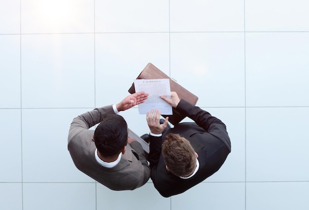 Dos hombres de negocios que firman un acuerdo, una mano sostiene el documento y la otra firma