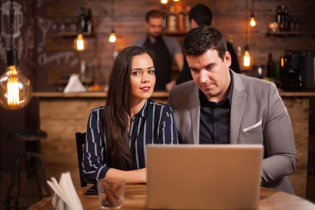 Dos hombres de negocios que tienen una reunión en una cafetería. Trabajando en una computadora portátil. Hablando de negocios.