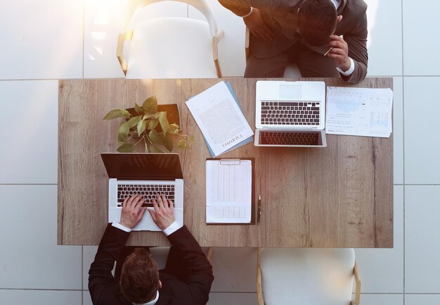 dos hombres de negocios sentados en una silla y viendo algo en una computadora portátil