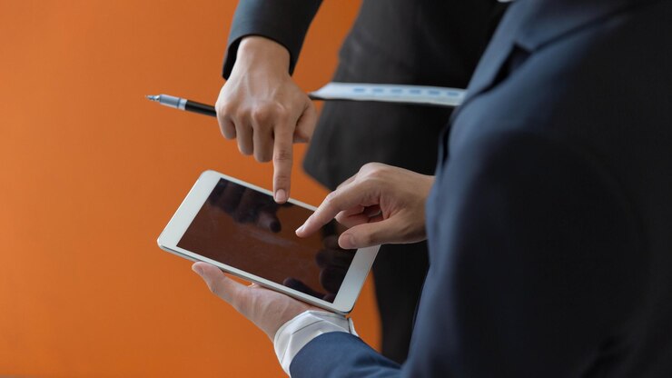 Foto dos hombres de negocios, uno sosteniendo la tableta y otro revisando los datos del documento
