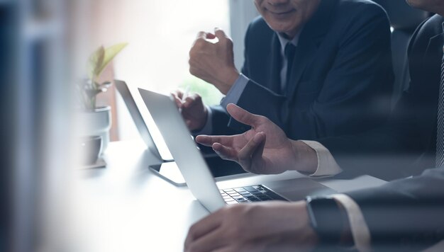 Dos hombres de negocios teniendo una discusión trabajando en una computadora portátil usando tableta digital y teléfono móvil en la oficina Planificación de negocios y solución trabajando juntos concepto de trabajo en equipo