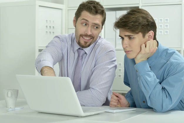 Dos hombres de negocios trabajando en una computadora portátil en la oficina