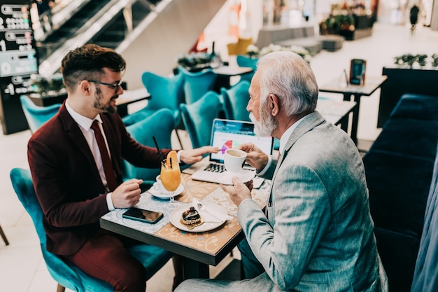 Dos hombres de negocios trabajando juntos en la cafetería moderna.