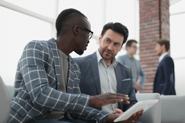 Dos hombres de negocios usan una tableta digital y tecnología.