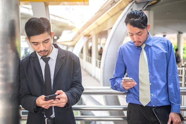 dos hombres de negocios usan teléfonos inteligentes en la ciudad, usan teléfono inteligente lism