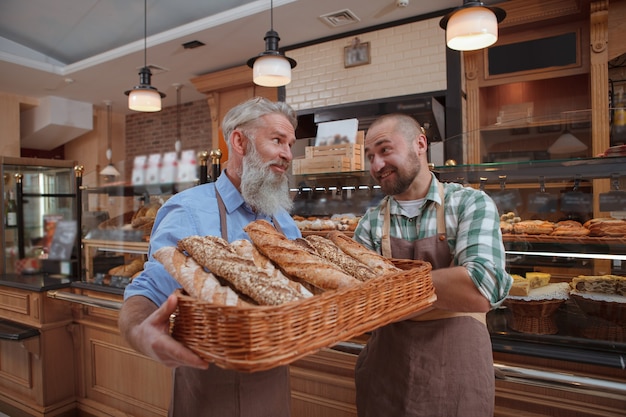 Dos hombres panaderos, padre e hijo, vendiendo pan delicioso en su panadería
