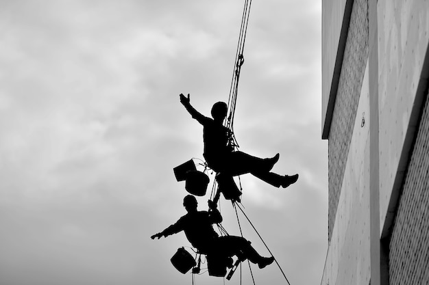 Foto dos hombres profesionales aíslan un edificio residencial en el exterior. alpinismo industrial. dos escaladores aíslan la pared de la casa con las cuerdas.