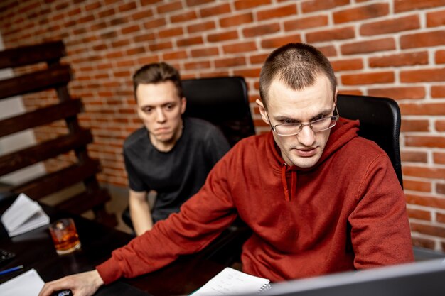 Dos hombres que trabajan en una oficina moderna. Consiguiendo los mejores resultados. Dos jóvenes confiados están discutiendo planes de negocios
