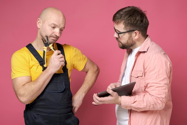 Dos hombres serios, un trabajador y un cliente, están discutiendo un proyecto mientras miran una tableta