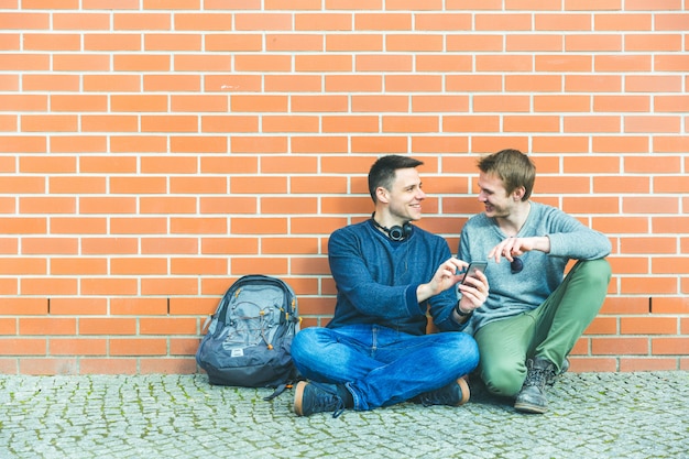 Dos hombres sonriendo y mirando teléfono inteligente