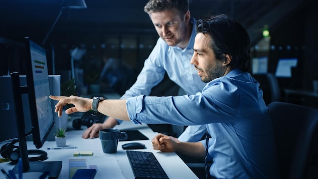 Foto dos hombres trabajando en una computadora con un reloj en la pantalla