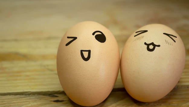 Dos huevos con emoticonos en el fondo de una tabla de madera
