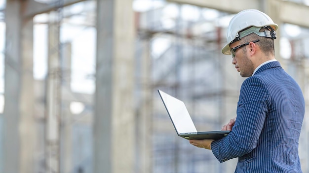 Dos ingenieros asiáticos que trabajan en el sitio de un gran proyecto de construcción Trabajan horas extras en el lugar de construcciónEquipo de ingenieros discuten en el sitioEl supervisor de arquitectos y el capataz se reúnen para discutir el diseño