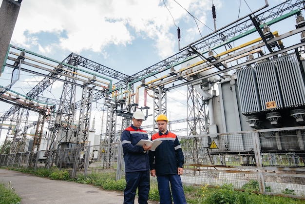 Dos ingenieros especializados en subestaciones eléctricas inspeccionan equipos modernos de alta tensión. Energía. Industria.