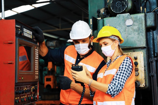 Dos ingenieros con mascarilla quirúrgica y trabajando en la fábrica.