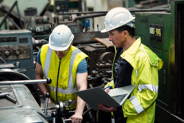 Dos ingenieros masculinos que planean producir autopartes con máquinas en una fábrica en Tailandia.