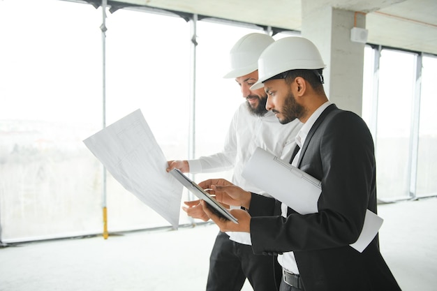 Dos ingenieros multirraciales del sitio de construcción del hombre de negocios