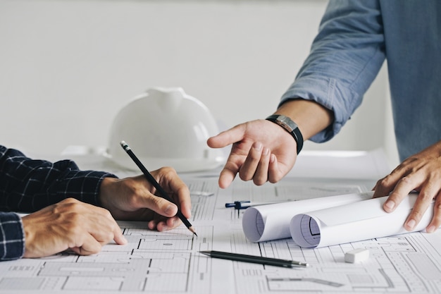 Dos ingenieros de obras de construcción de hombre de negocios trabajando en el plano y discutiendo el piso