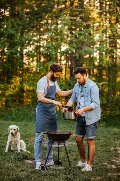 Dos joven haciendo barbacoa al aire libre