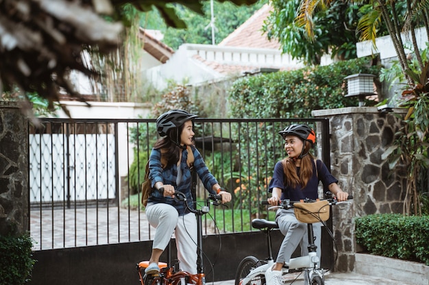 Dos jovencitas están listas para ir a la escuela plegando bicicleta