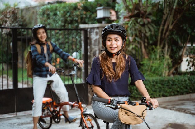 Dos jovencitas están listas para ir a la escuela plegando bicicleta