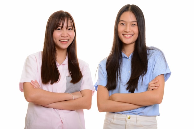 Dos jóvenes adolescentes asiáticas felices sonriendo con los brazos cruzados