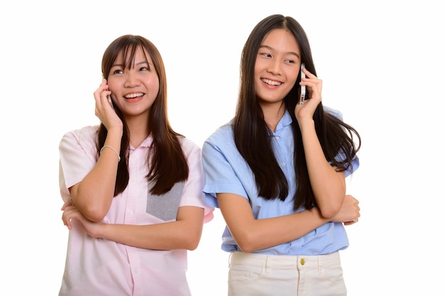 Dos jóvenes adolescentes asiáticas felices sonriendo y hablando por mobil