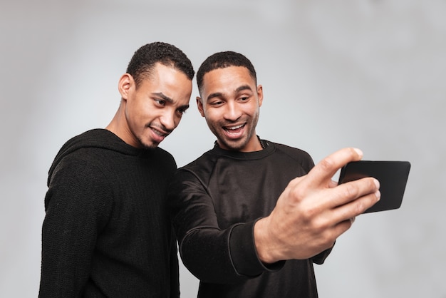 Dos jóvenes africanos alegres hacen una selfie.