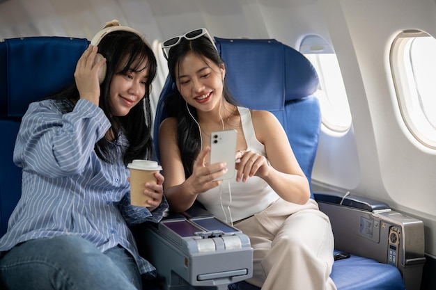 Dos jóvenes amigas asiáticas felices disfrutan hablando durante el vuelo.