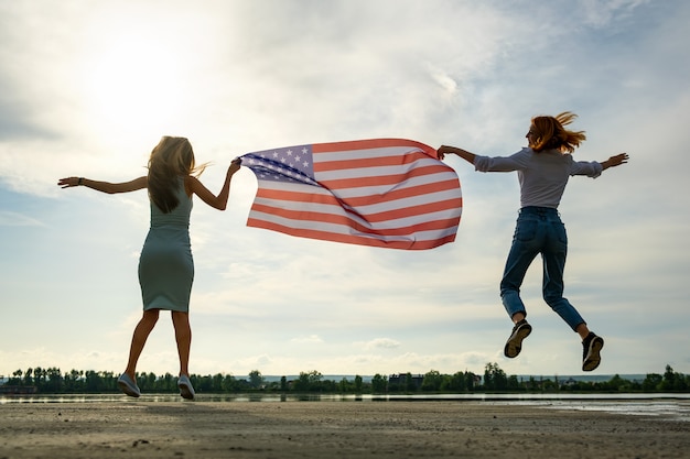 Dos jóvenes amigas con bandera nacional de Estados Unidos