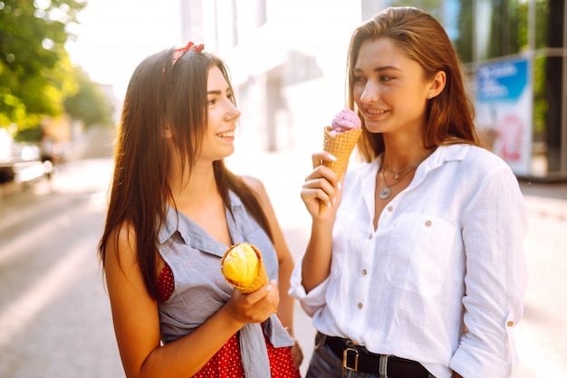 Dos jóvenes amigas divirtiéndose y comiendo helado.