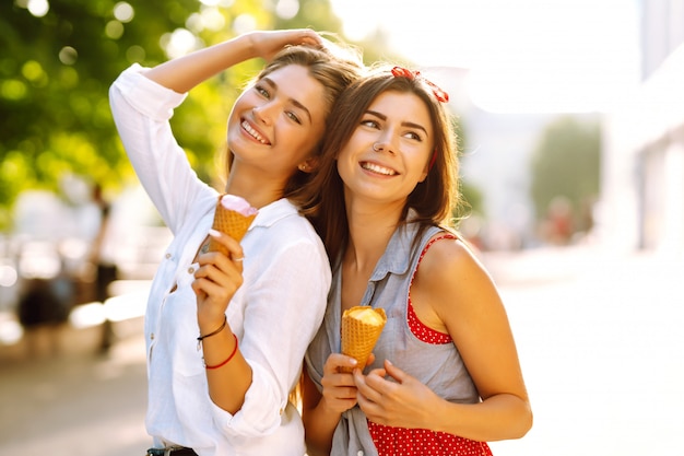 Dos jóvenes amigas divirtiéndose y comiendo helado.