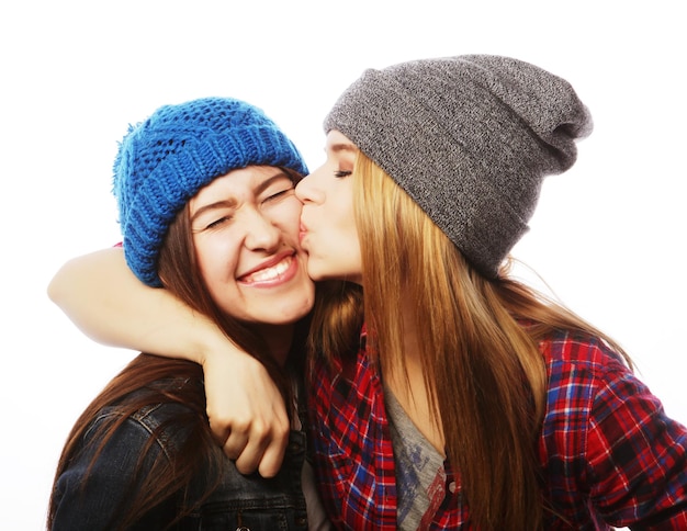 Dos jóvenes amigas de pie juntas y divirtiéndoseAisladas en blanco