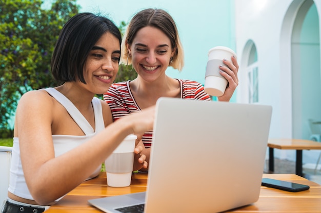 Dos jóvenes amigos usando una computadora portátil en la cafetería.