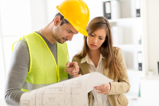 Foto dos jóvenes arquitectos discutiendo planes de construcción en el cargo.