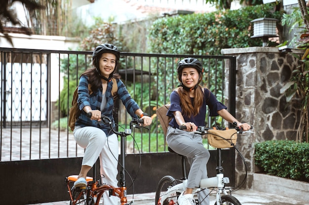 Dos jóvenes asiáticos con casco y bolsas listos van al campus