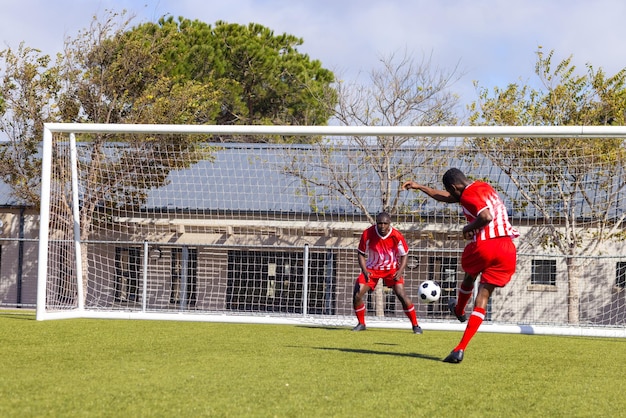 Dos jóvenes atletas afroamericanos están jugando al fútbol en el campo al aire libre uno pateando la pelota