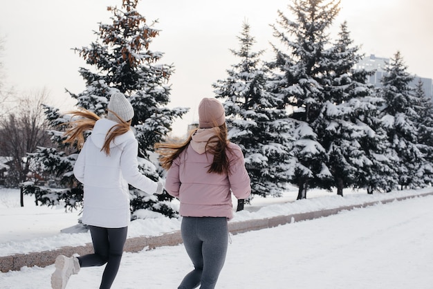 Dos jóvenes atléticas corriendo en el parque en un día soleado de invierno. Una forma de vida sana.