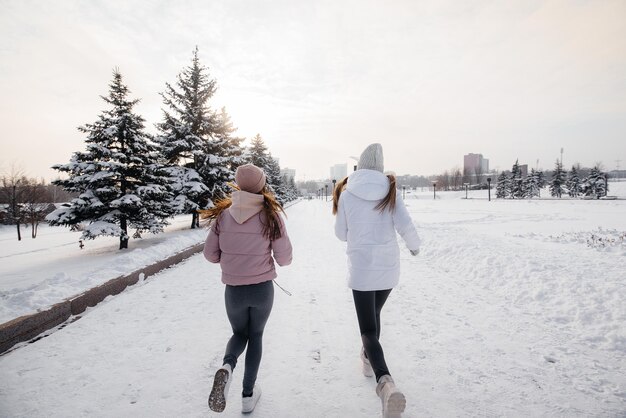 Dos jóvenes atléticas corriendo en el parque en un día soleado de invierno. Una forma de vida sana.