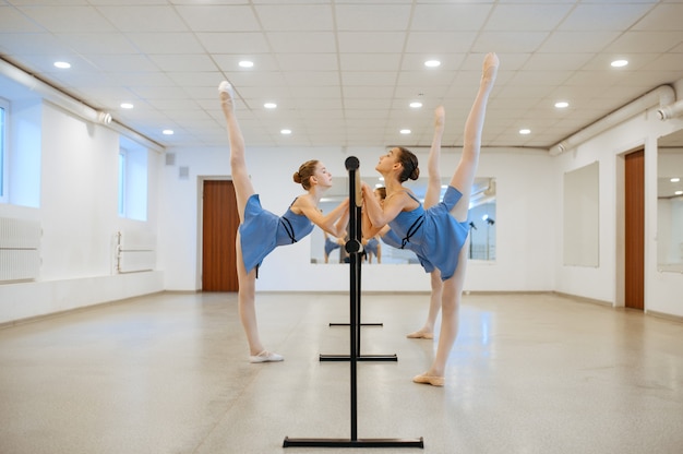 Dos jóvenes bailarinas ensayando en la barra en clase. Escuela de ballet, bailarinas en lección de coreografía, niñas practicando Grace Dance