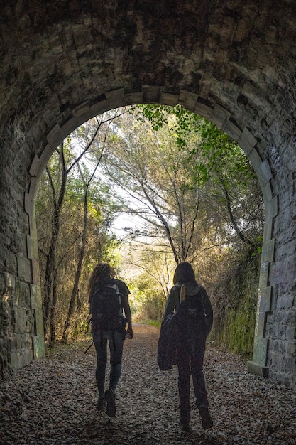 Dos jóvenes caminando dentro de un túnel en la costa entre Deba y Zumaia