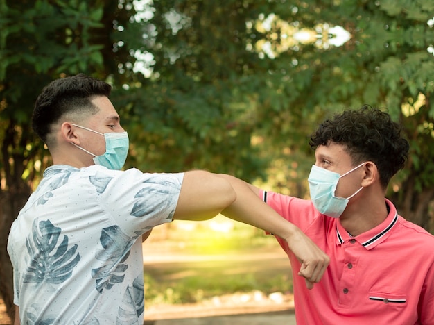 Dos jóvenes chocando sus codos, imagen de dos jóvenes chocando sus codos de manera amistosa, sobre dos codos chocando de manera amistosa