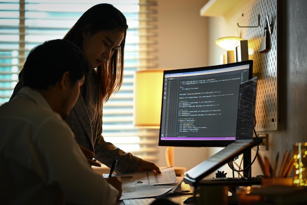 Dos jóvenes colegas discutiendo y trabajando en un proyecto de Inteligencia Artificial en la oficina en casa