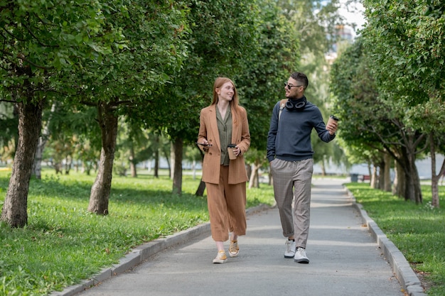 Dos jóvenes colegas en ropa casual caminando por el parque