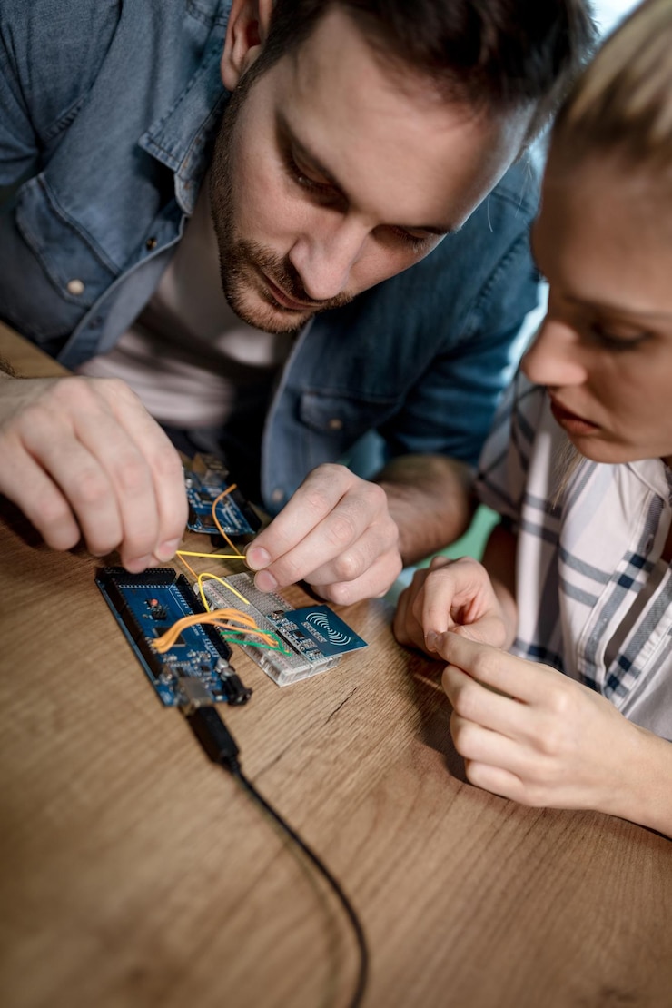Foto dos jóvenes compañeros técnicos centrados en la reparación de equipos electrónicos.