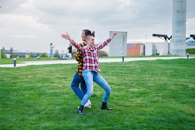 Dos jóvenes de diferentes nacionalidades bailando al aire libre en un parque