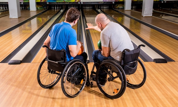 Dos jóvenes discapacitados en sillas de ruedas jugando a los bolos en el club