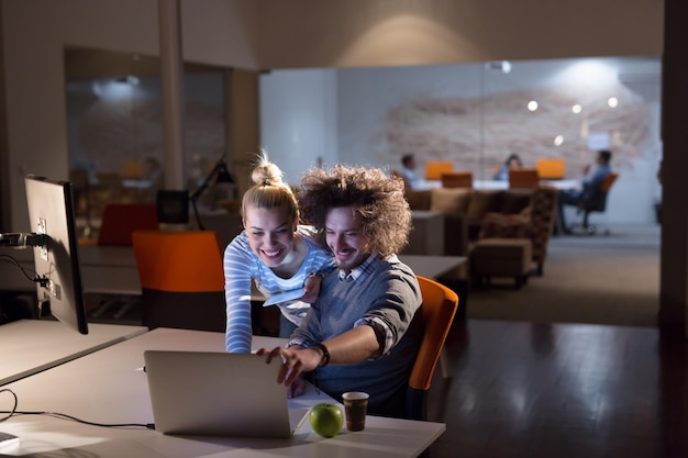 Dos jóvenes diseñadores están trabajando en un nuevo proyecto en la oficina nocturna utilizando tecnología moderna.