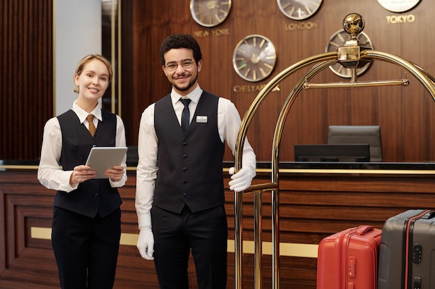 Dos jóvenes y elegantes empleados de un lujoso hotel esperando nuevos huéspedes