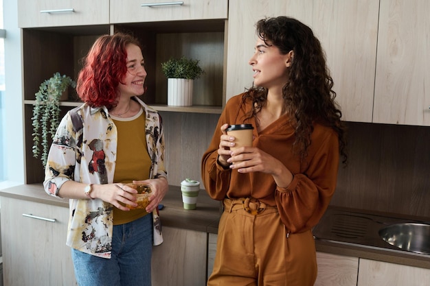 Dos jóvenes empleadas elegantes con ropa informal elegante charlando en el descanso